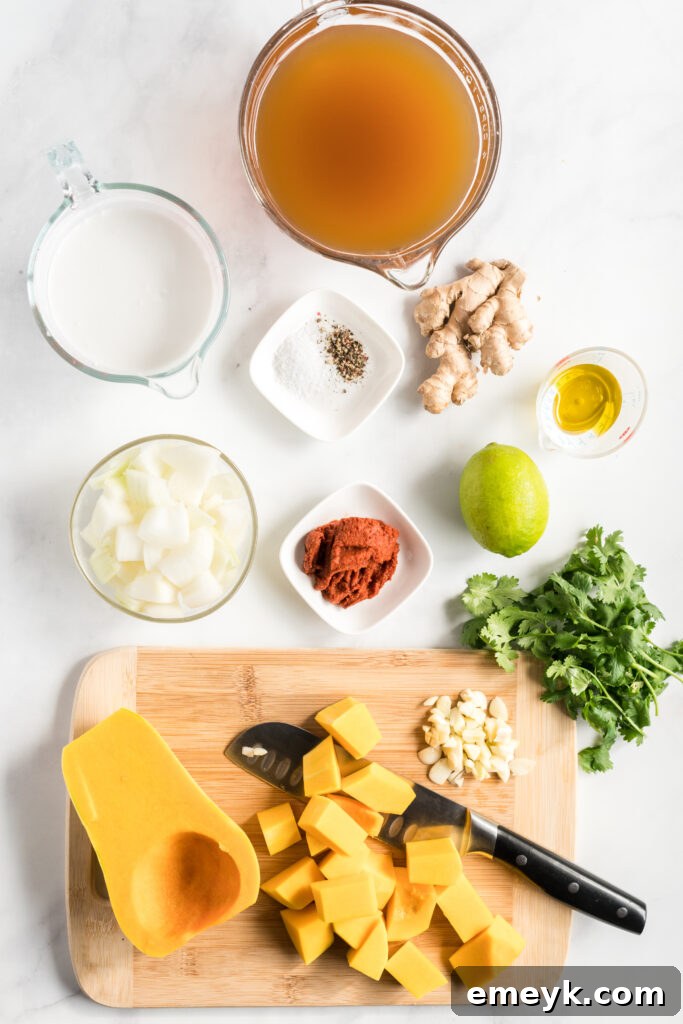 A flat lay photograph showcasing the fresh ingredients for Curried Butternut Squash Soup: cubed squash, ginger, garlic, red curry paste, and a can of coconut milk.