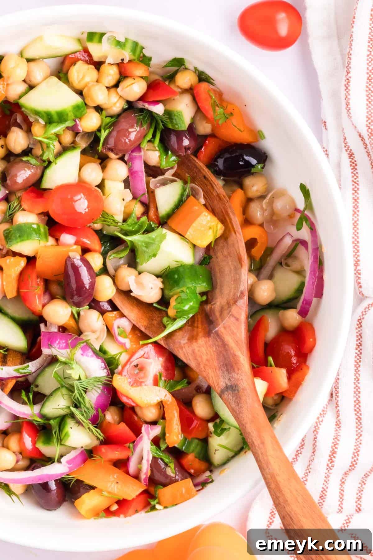 Mediterranean Chickpea Salad with a wooden spoon, ready to be served