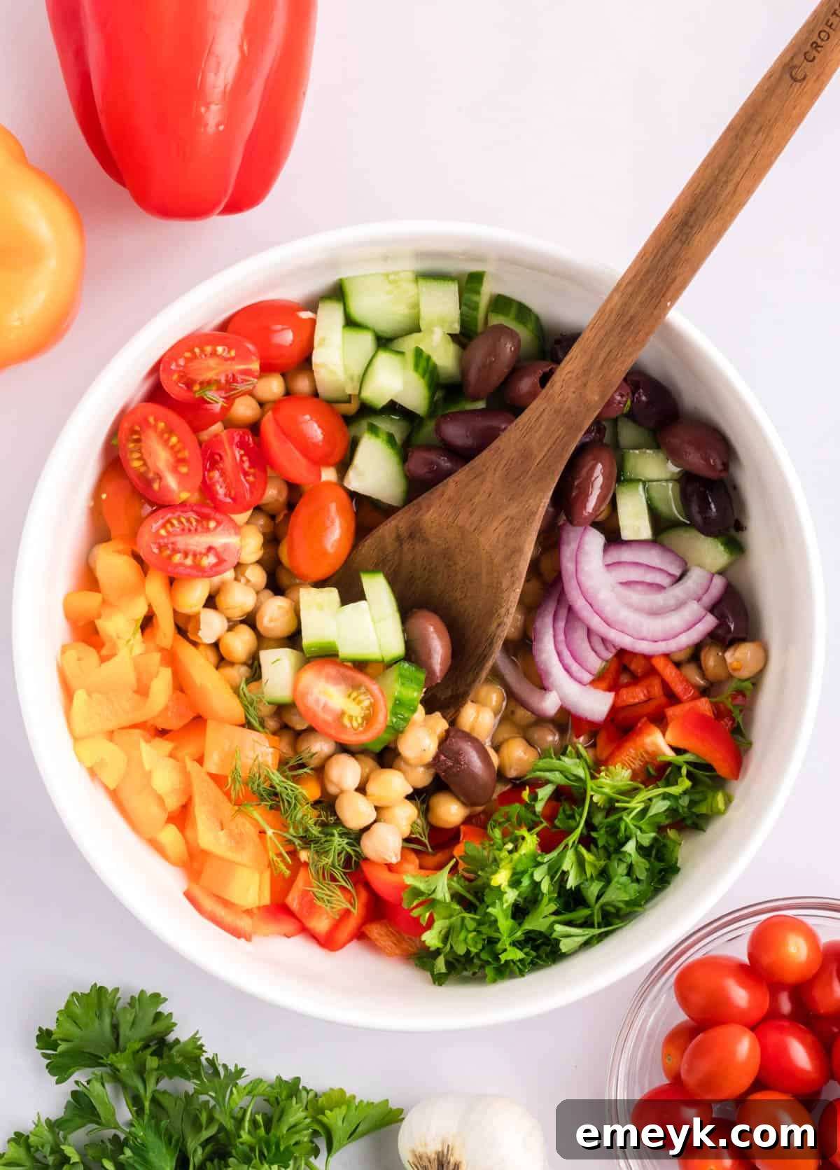 Mediterranean Chickpea Salad with dressing added into ingredients, being tossed.