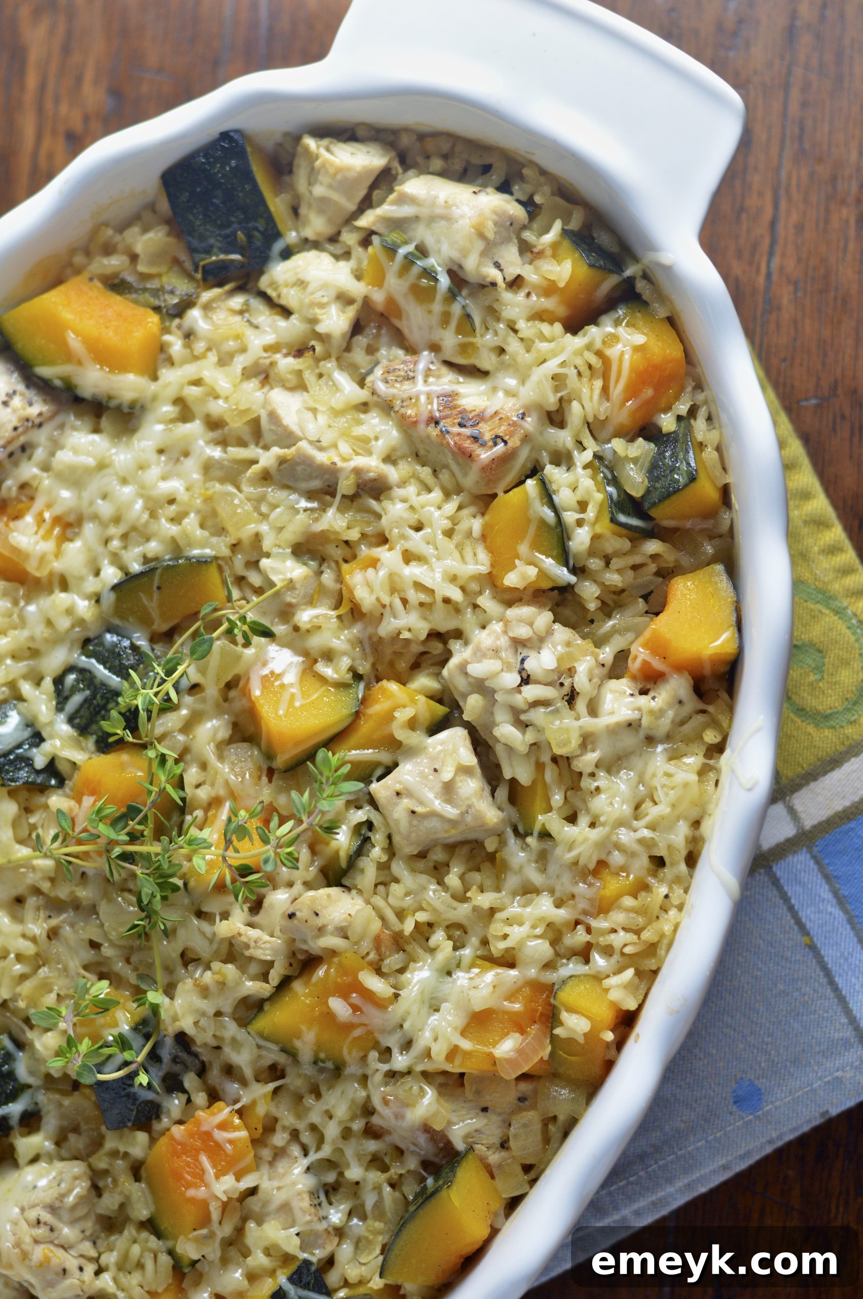 Baked Chicken Kabocha Squash Risotto Recipe in a white casserole dish, garnished with fresh thyme.