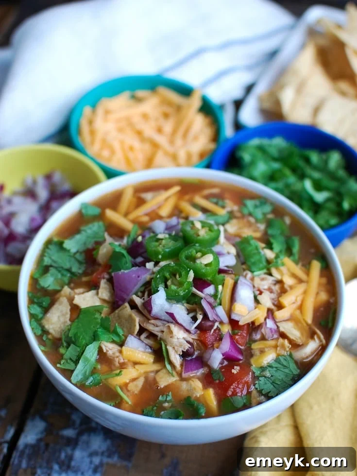 A steaming bowl of Slow Cooker Chicken Tortilla Soup garnished with fresh cilantro and lime