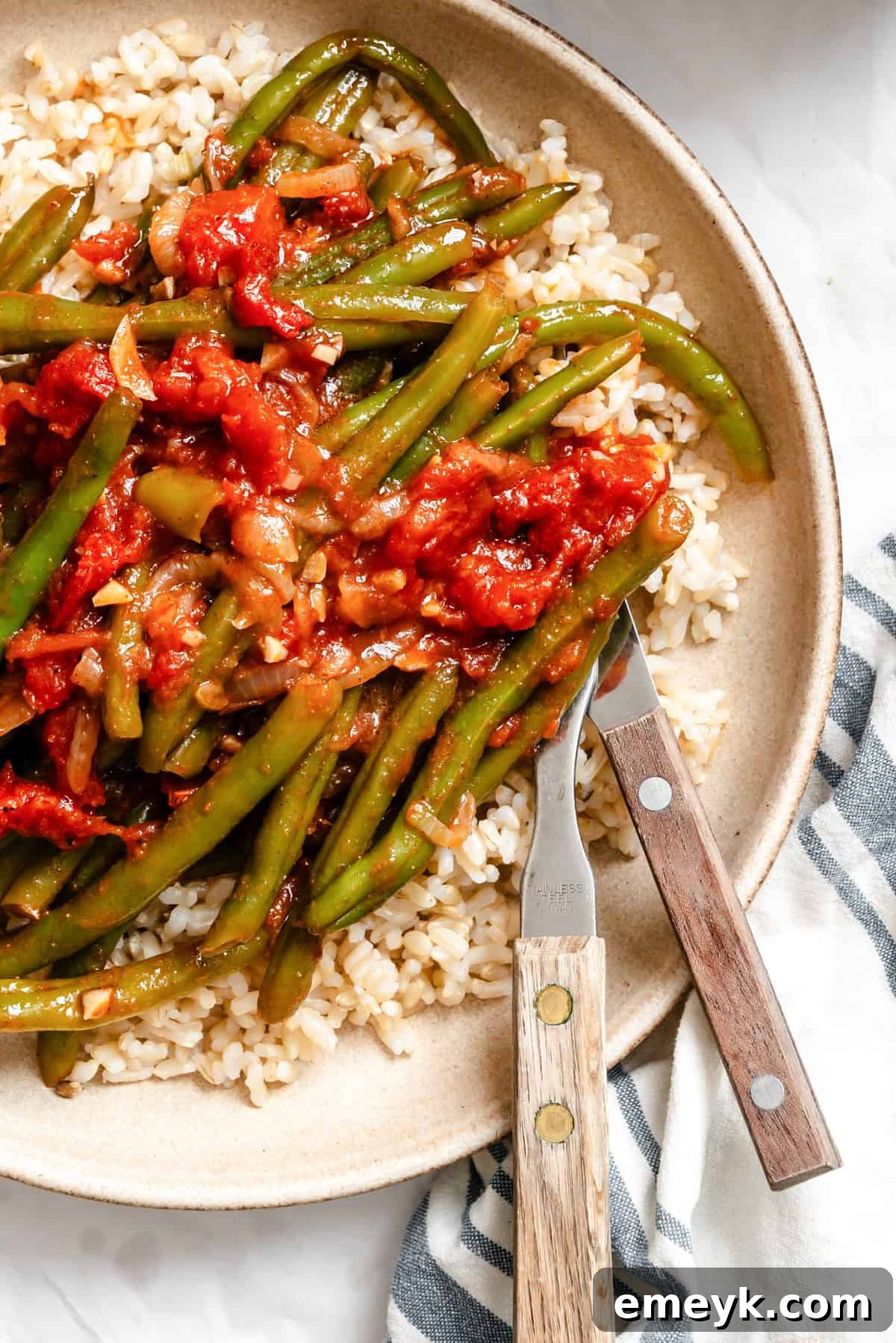 Lebanese Green Beans served in a white bowl with a fork and knife, ready to eat