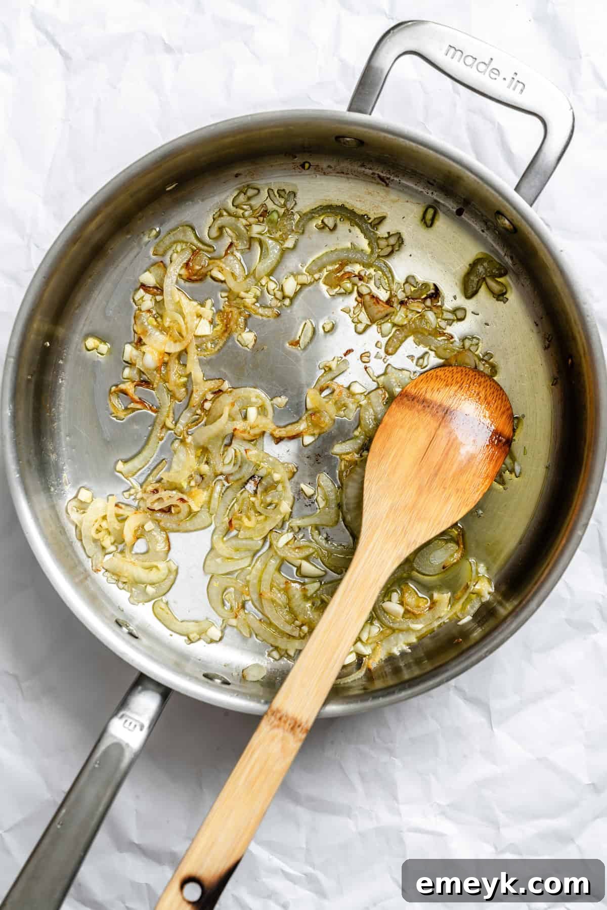 Onion and garlic sautéing in a large pan with olive oil, forming the aromatic base for the Lebanese Green Beans