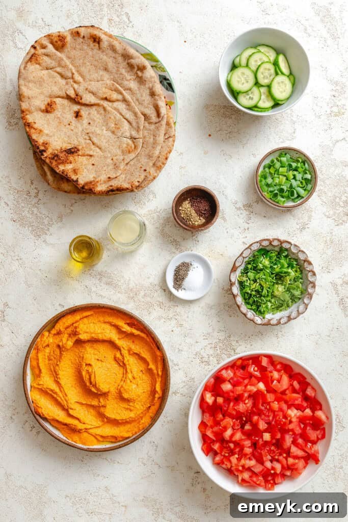 Assorted ingredients for Mediterranean Naan Pizza, including fresh vegetables, hummus, and naan bread