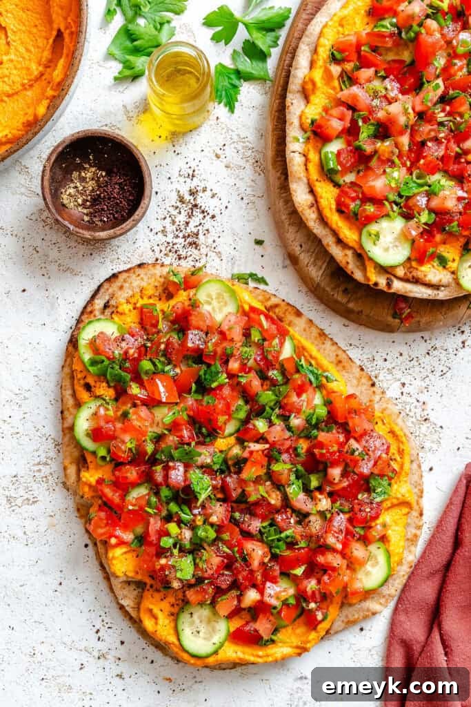 Mediterranean Naan Pizza on a white cutting board, dusted with sumac, ready to be sliced