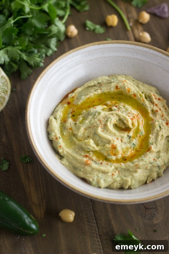 A bowl of vibrant Cilantro Lime Hummus, garnished with fresh cilantro and a lime wedge, offering a zesty and refreshing twist on classic hummus.