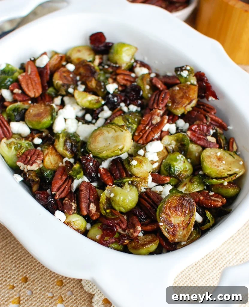 Roasted Brussels Sprouts with Cranberries, Blue Cheese, and Pecans in a white serving bowl.