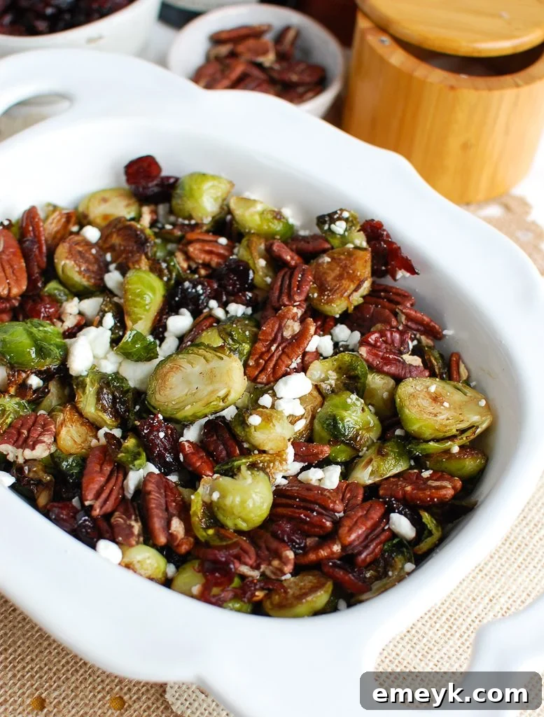 Serving bowl of roasted Brussels Sprouts with Cranberries and goat cheese crumbles visible.