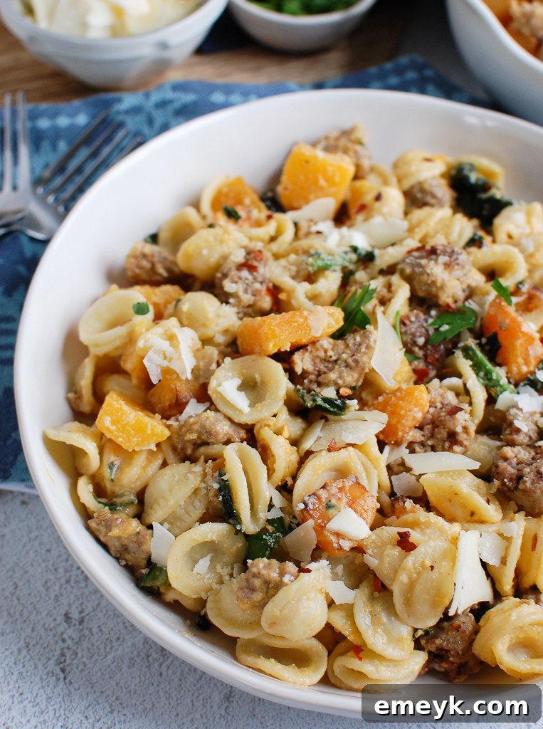 Golden Butternut Squash Pasta with Savory Sausage 2 Butternut Squash Pasta in a white bowl, garnished with fresh herbs and parmesan cheese
