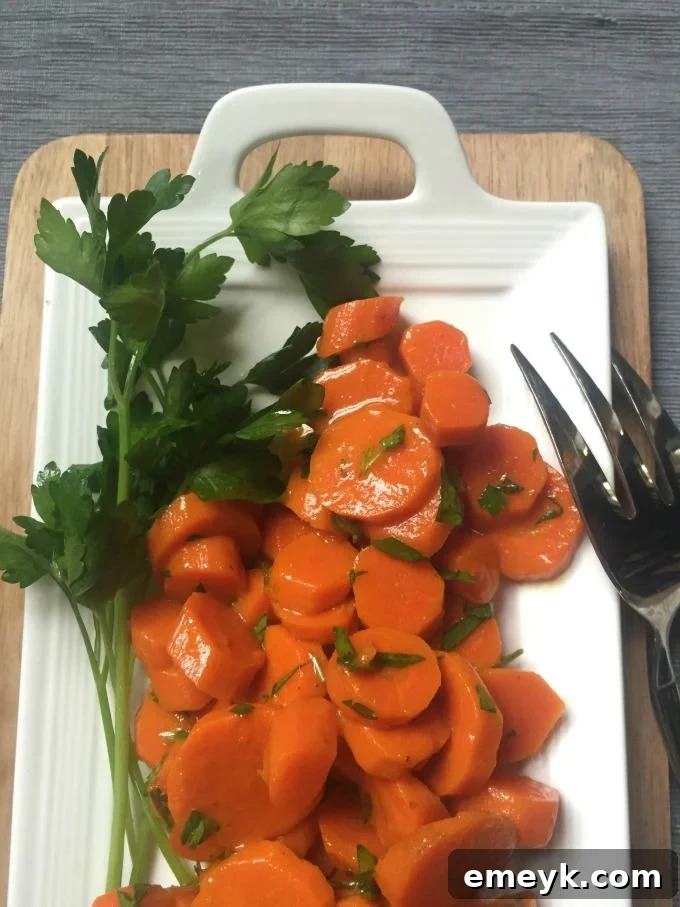 Close-up of vibrant honey glazed carrots garnished with fresh parsley on a platter.