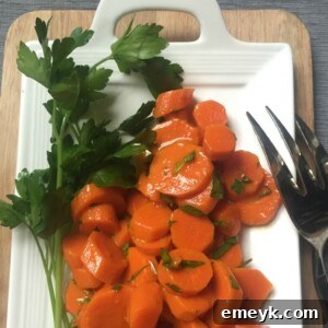 A bowl of glossy honey glazed carrots, garnished with fresh green parsley.