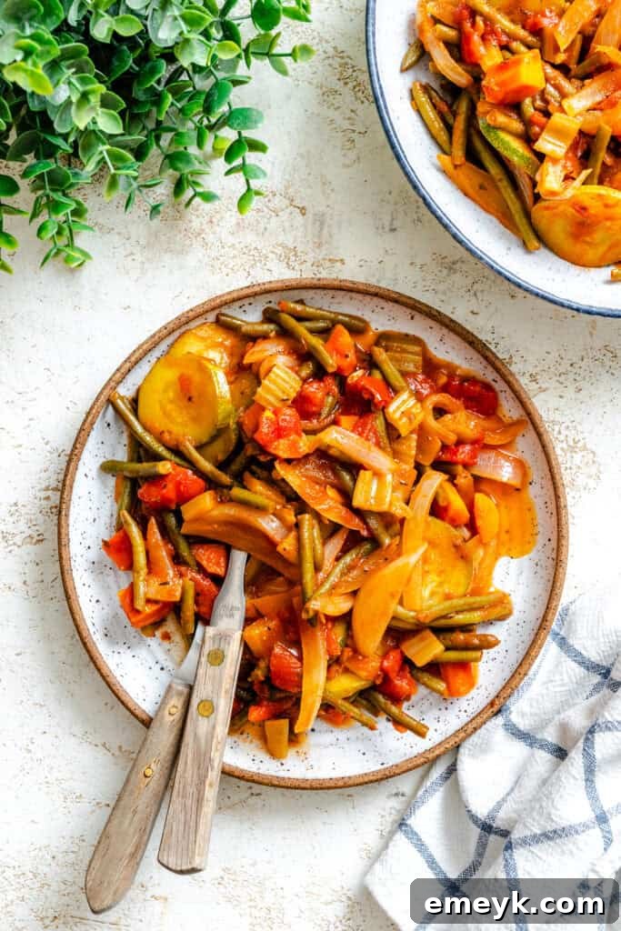 A serving of Lebanese Vegetables (Loubieh bi Zeit) on a white plate, showcasing the vibrant colors of green beans, zucchini, and tomatoes.