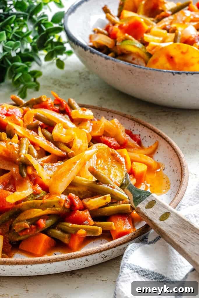 A close-up shot of Lebanese Vegetables (Loubieh bi Zeit) in a pan with a serving spoon, highlighting the rich tomato sauce and tender cooked vegetables.