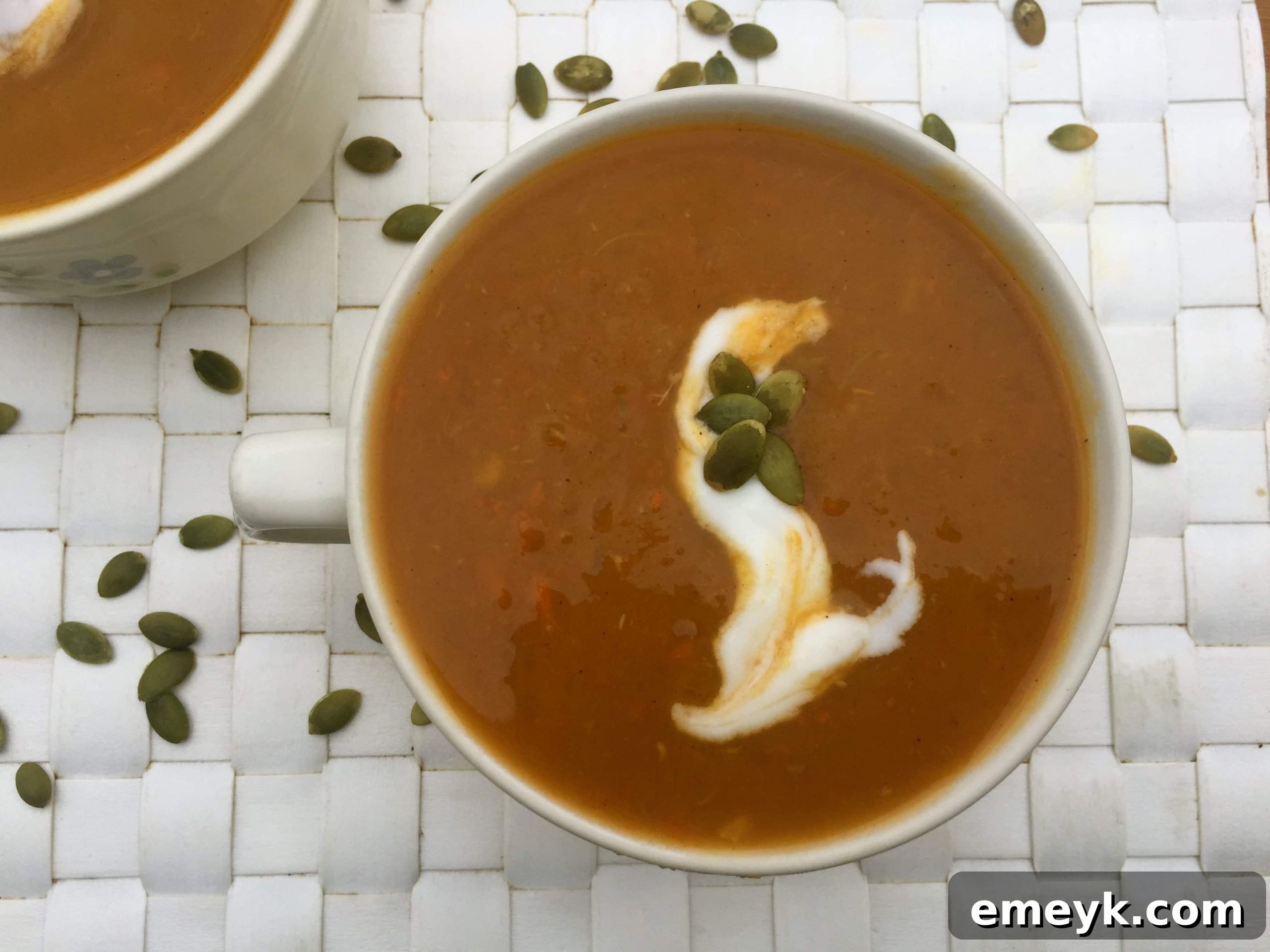 Close-up of creamy Slow Cooker Butternut Squash Sweet Potato Soup, garnished with yogurt and pumpkin seeds.