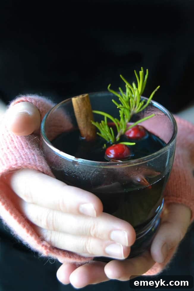 41 Festive Season Sips 3 A steaming mug of slow cooker mulled wine garnished with orange slices and cinnamon sticks, perfect for holiday gatherings.