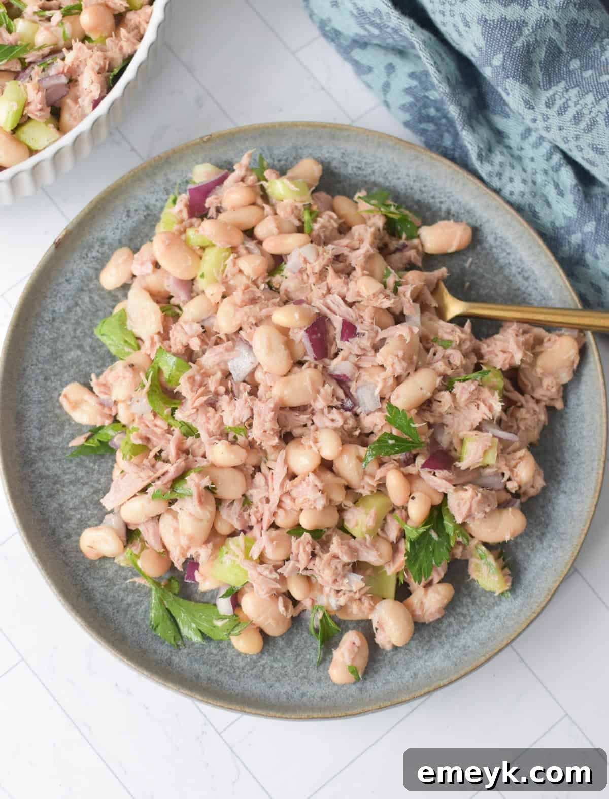 Fresh White Bean and Tuna Salad served on a rustic blue plate, garnished with fresh parsley.