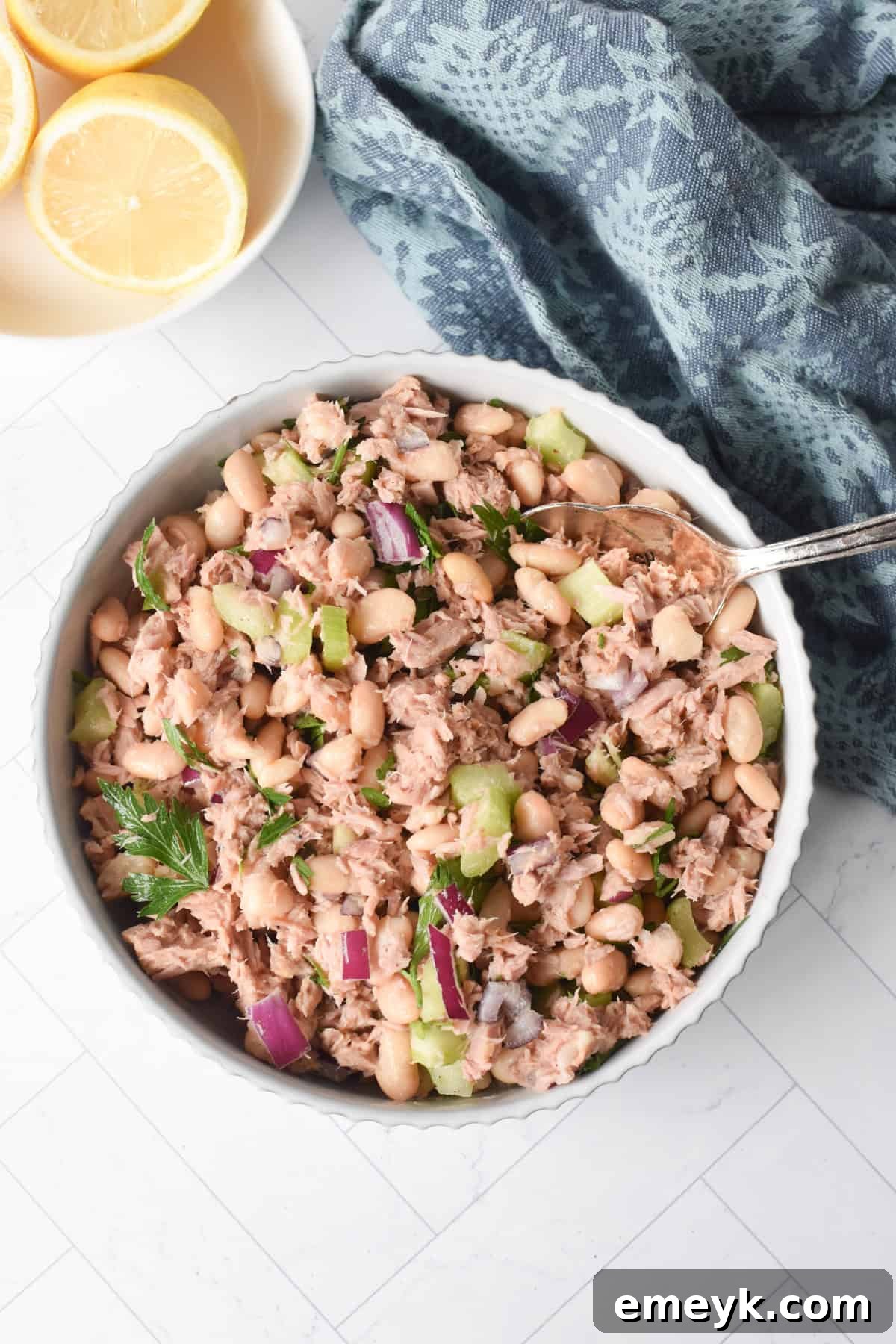 Close-up of Tuna and White Bean Salad in a pristine white bowl with a fork, ready to be enjoyed.