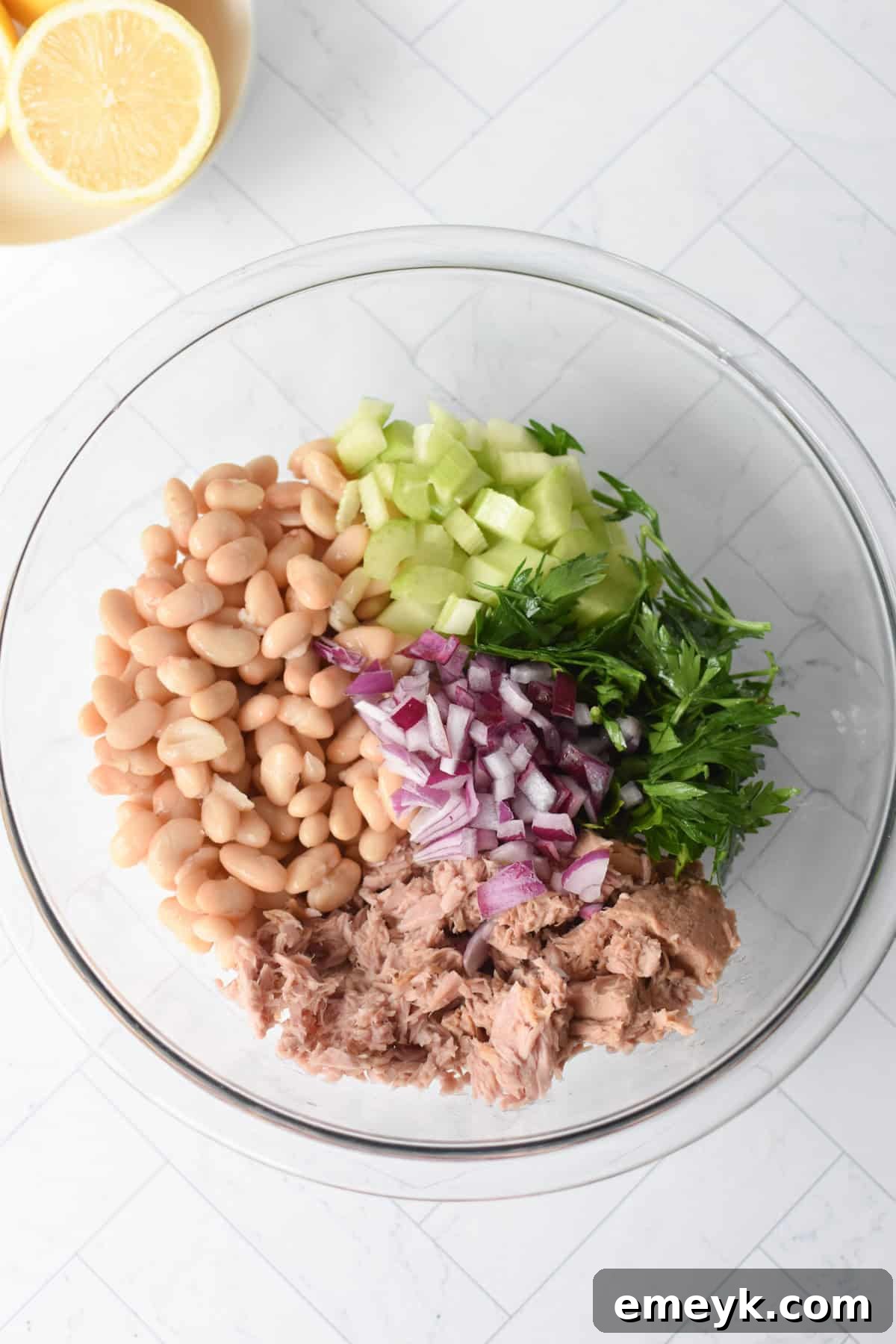 Step 1: Combining white beans, tuna, and fresh vegetables in a large glass bowl.