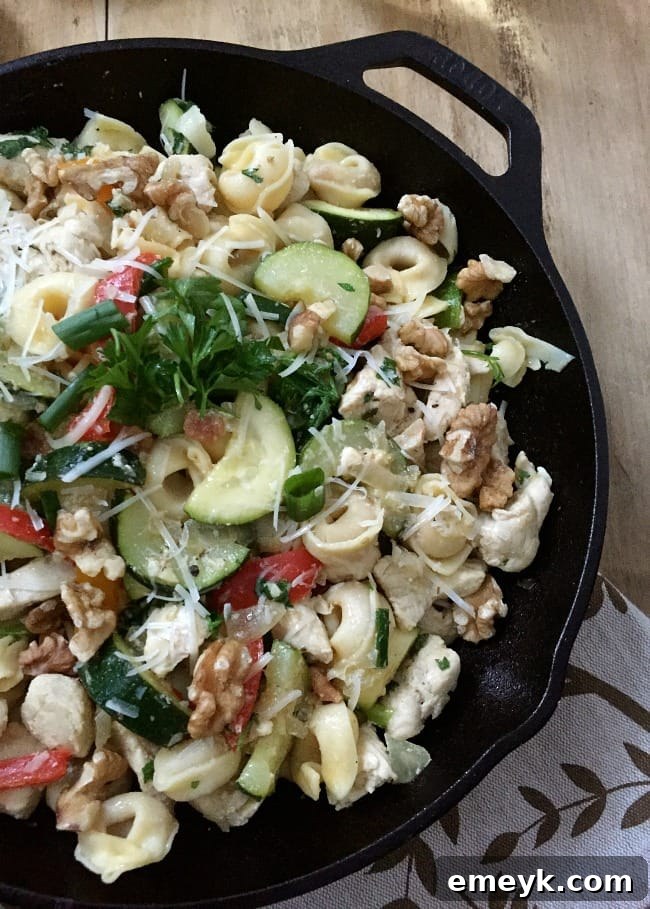 A vibrant 30 Minute Chicken Tortellini Skillet cooked in a cast iron pan, showing chicken pieces, colorful vegetables, and tortellini