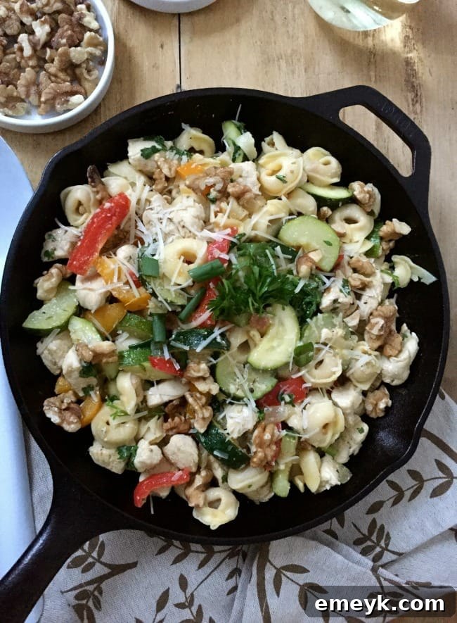 A serving of 30 Minute Chicken Tortellini Skillet topped with grated Parmesan and walnuts