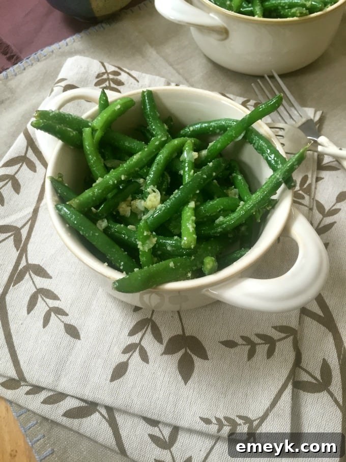 Close-up of freshly cooked Garlic Parmesan Green Beans in a skillet, showcasing the golden-brown garlic and melted Parmesan cheese clinging to the beans.