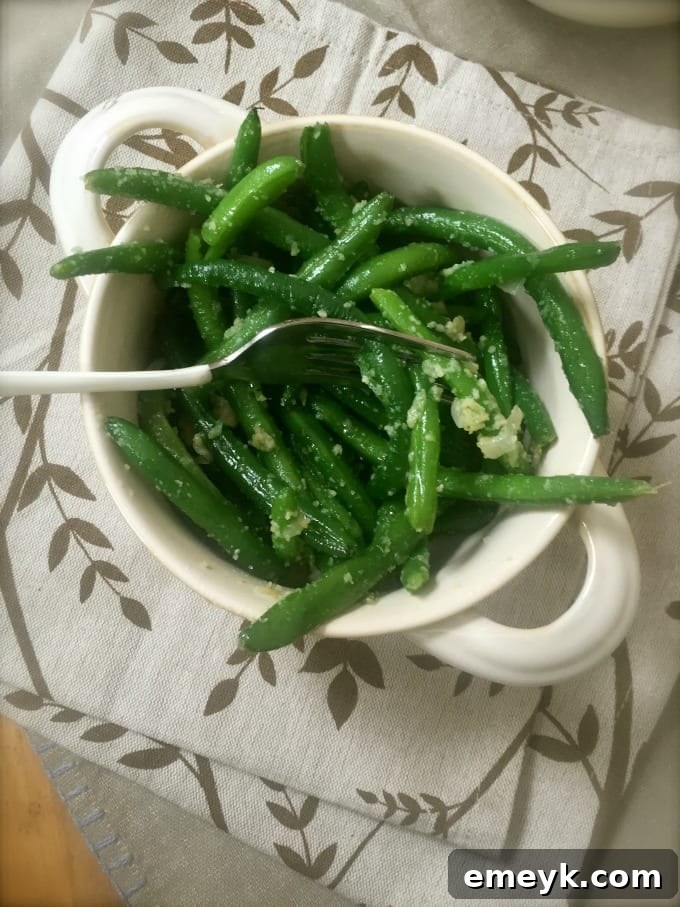 Garlic Parmesan Green Beans elegantly served hot on a clean white plate, suitable for both a cozy family dinner and an elaborate holiday feast.