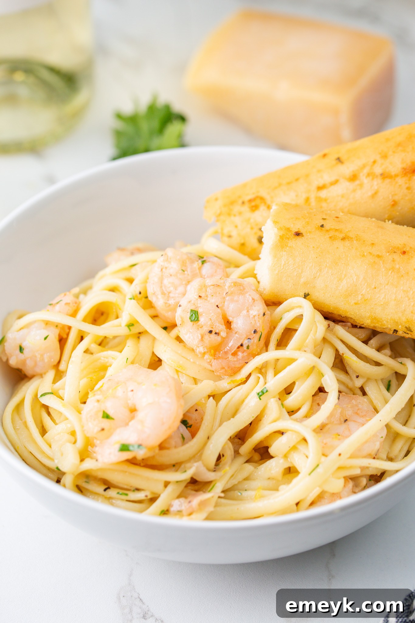 Lemon Garlic Shrimp Pasta served on a white plate with a breadstick, ready to eat.