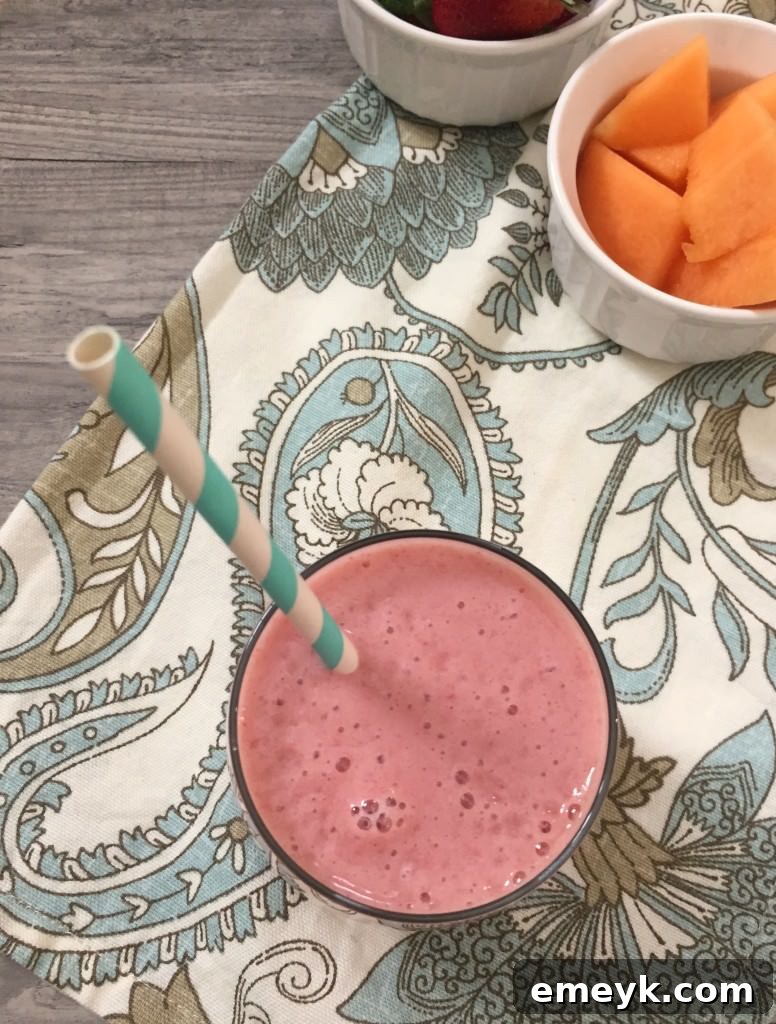 Close-up of a Strawberry Cantaloupe Smoothie with a straw, showing its vibrant color and smooth texture.