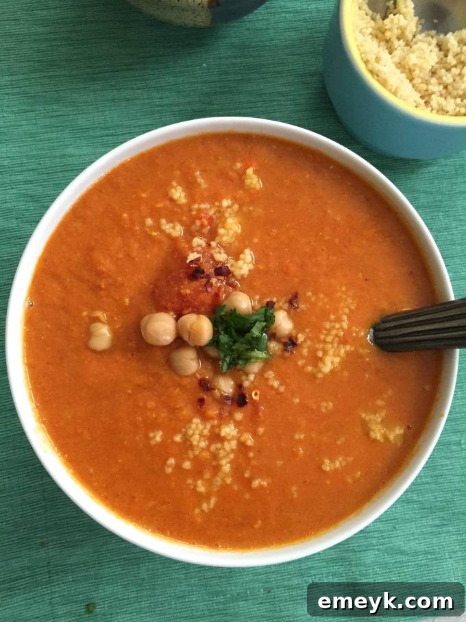 Close-up of vibrant Moroccan Tomato Couscous Chickpea Soup simmering in a pot, showcasing its rich texture and colors.