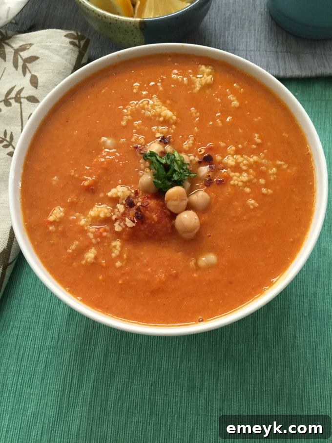 A bowl of Moroccan Tomato Couscous Chickpea Soup with fresh cilantro and Naan bread on the side.