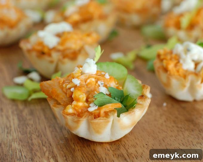 Buffalo Chicken Hummus Bites arranged on a wooden board, garnished with fresh celery.