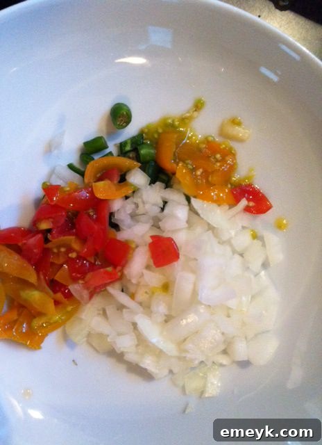 Close-up of finely chopped vegetables, including bell peppers, onions, and chili peppers, in a bowl