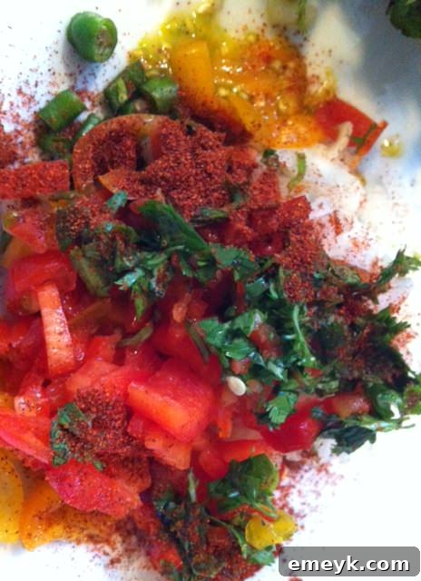 Chopped vegetables in a mixing bowl, topped with fresh cilantro leaves and crushed red pepper flakes