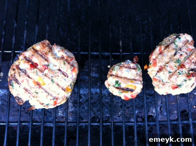 Spicy turkey burgers cooking on a hot grill, showing excellent grill marks and active sizzling