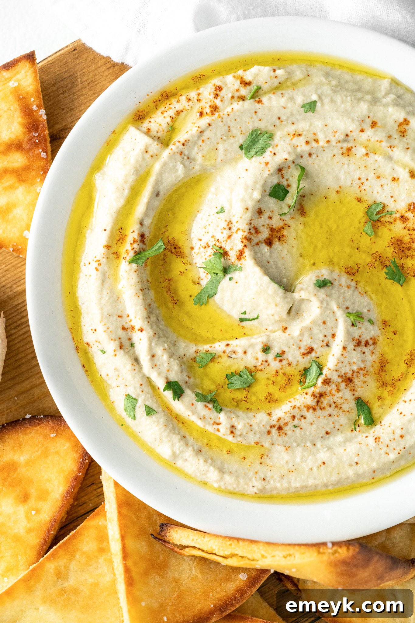 Baba Ghanoush in a white bowl, garnished with fresh herbs and olive oil.