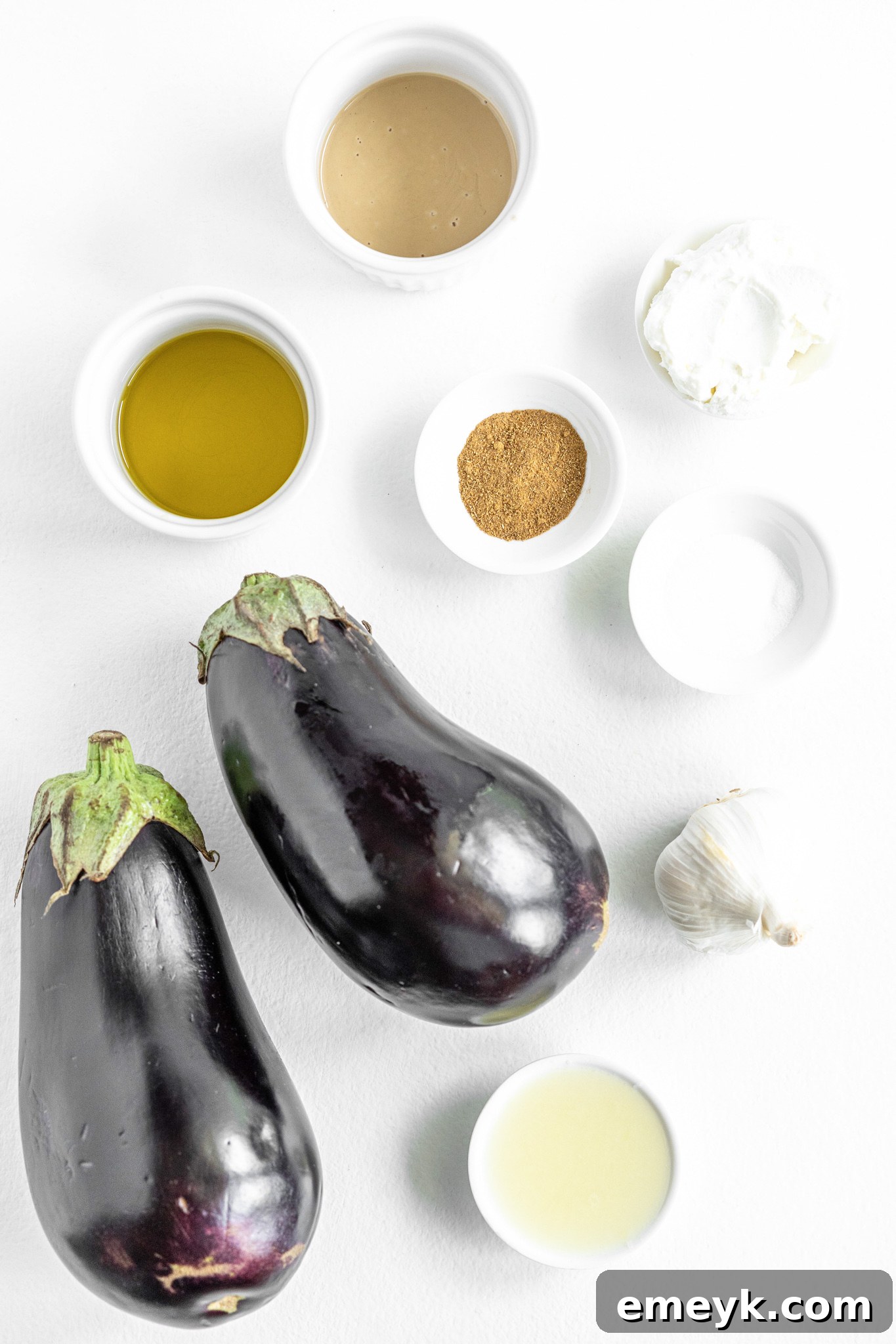 Fresh ingredients for Baba Ghanoush, including eggplant, tahini, lemon, and garlic.