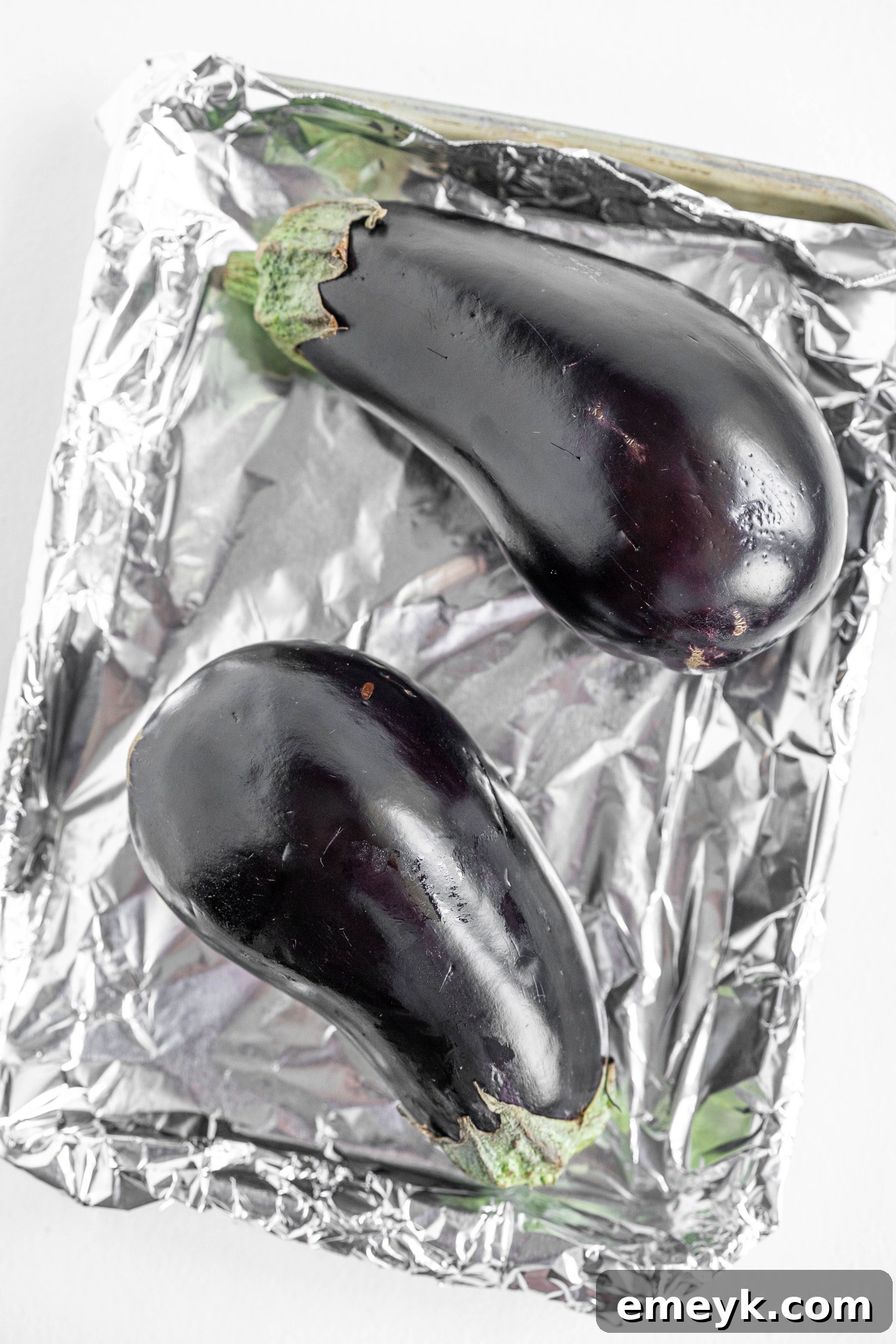 Whole eggplants on a baking tray, prepared for roasting for Baba Ghanoush.