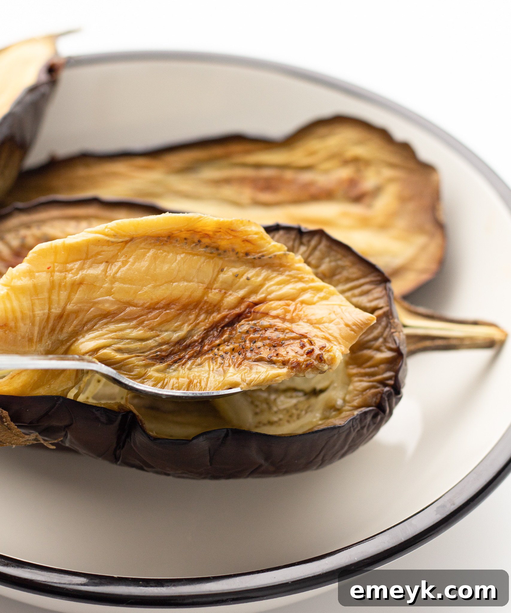 Flesh being scooped out of an air-fried eggplant.