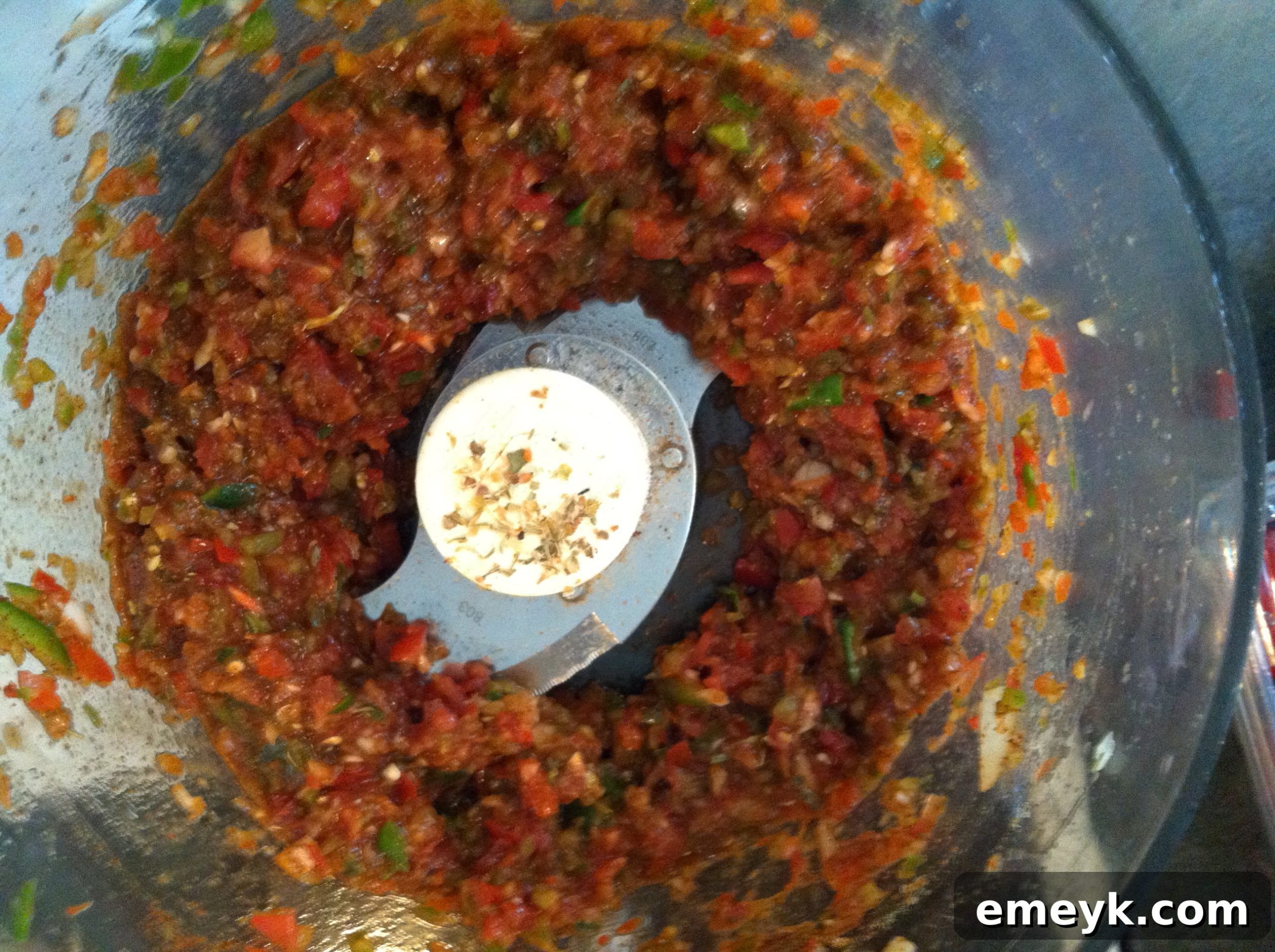 Partially processed salsa ingredients in a food processor, showing textured consistency.