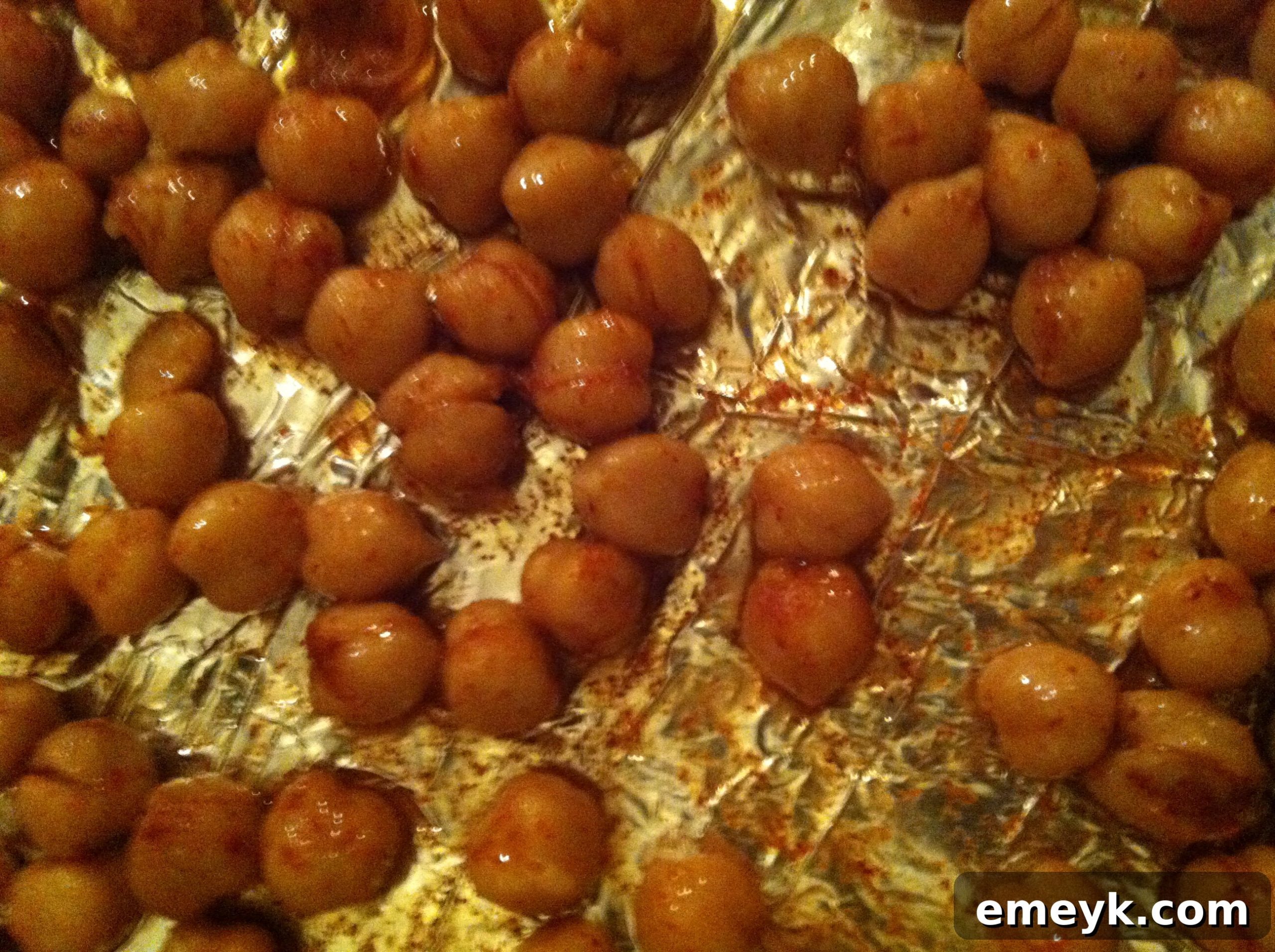 Seasoned chickpeas spread evenly in a single layer on a baking sheet, ready for the oven.