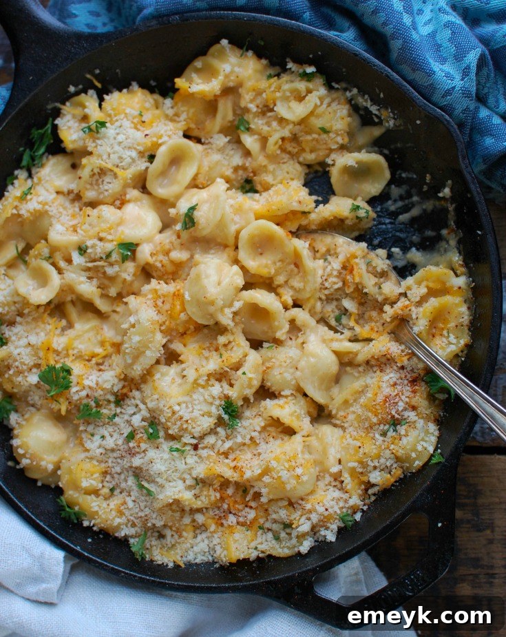 Baked mac and cheese with panko breadcrumbs, served with a spoon in a pan.