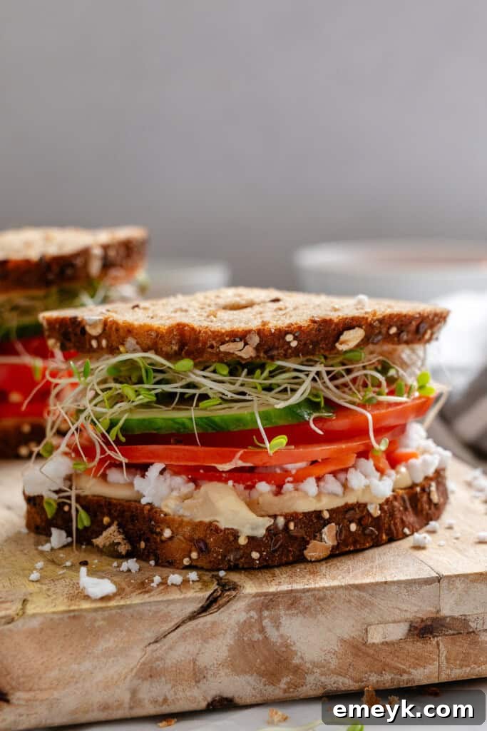 A freshly prepared Mediterranean Vegetable Sandwich on a wooden cutting board.