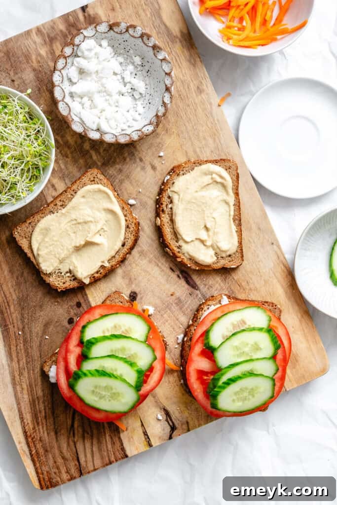 Tomato and cucumber slices arranged on hummus-spread bread.