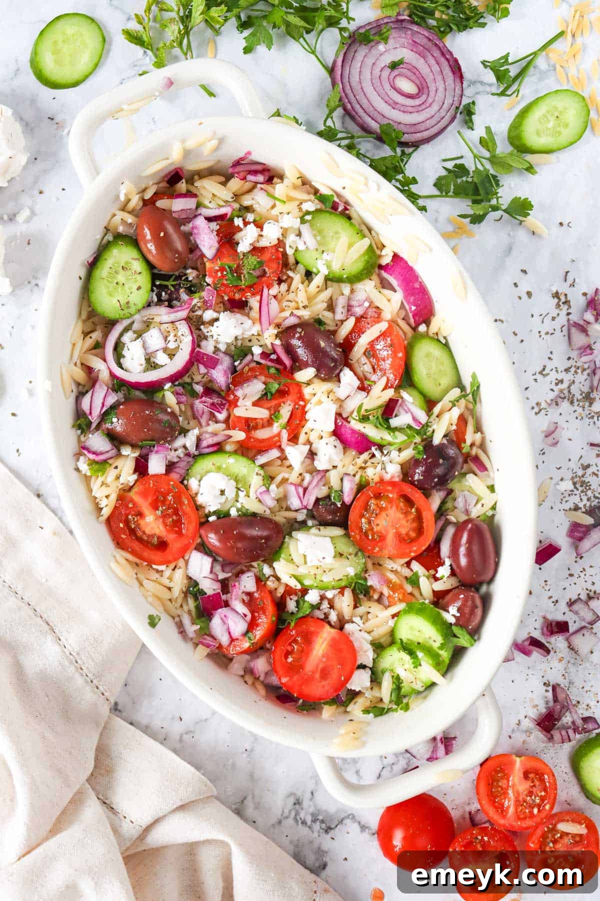 Two white bowls filled with Greek Orzo Pasta Salad, garnished with fresh herbs