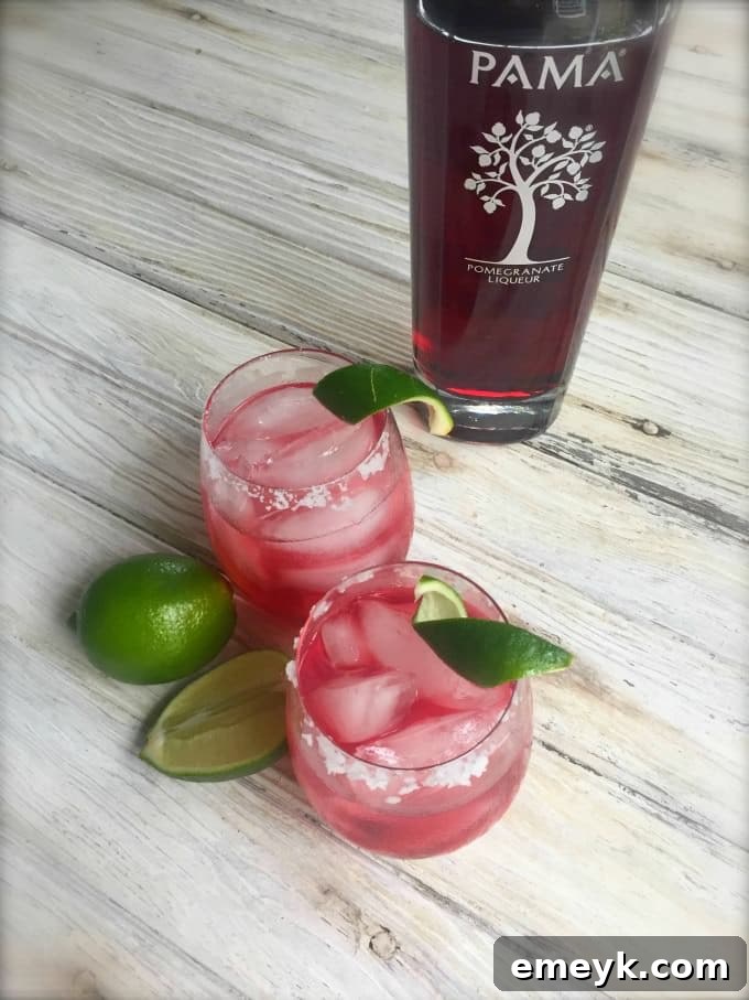 Ruby Pomegranate Margarita 3 Close-up of a Pomegranate Margarita showing the beautiful red color and lime garnish in a summer setting.