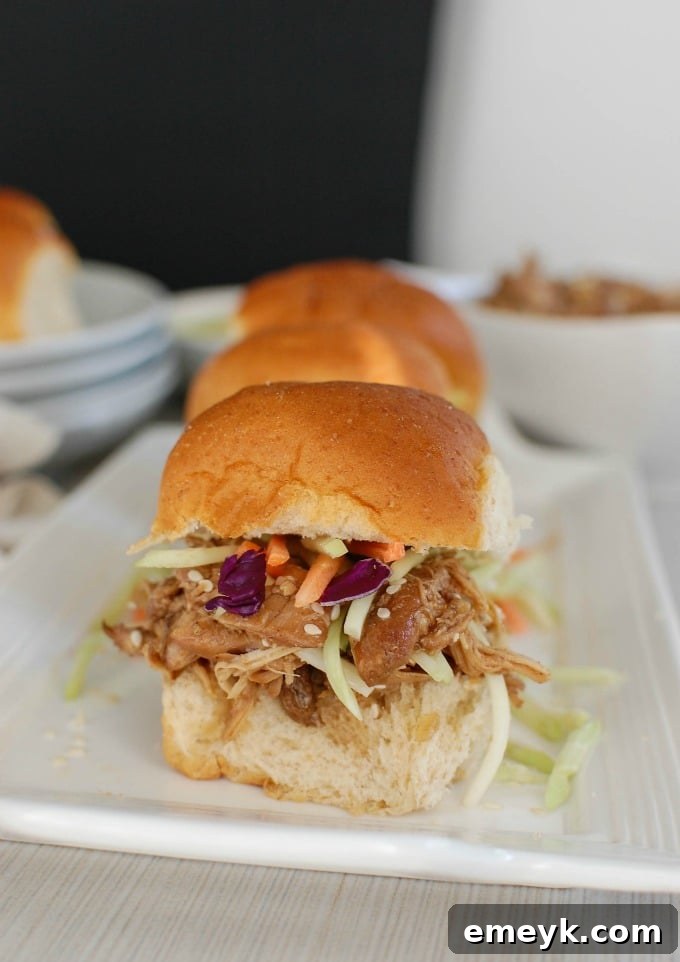 Delicious Slow Cooker Asian Honey Sesame Chicken Sliders garnished with fresh cilantro and sesame seeds, ready to serve.