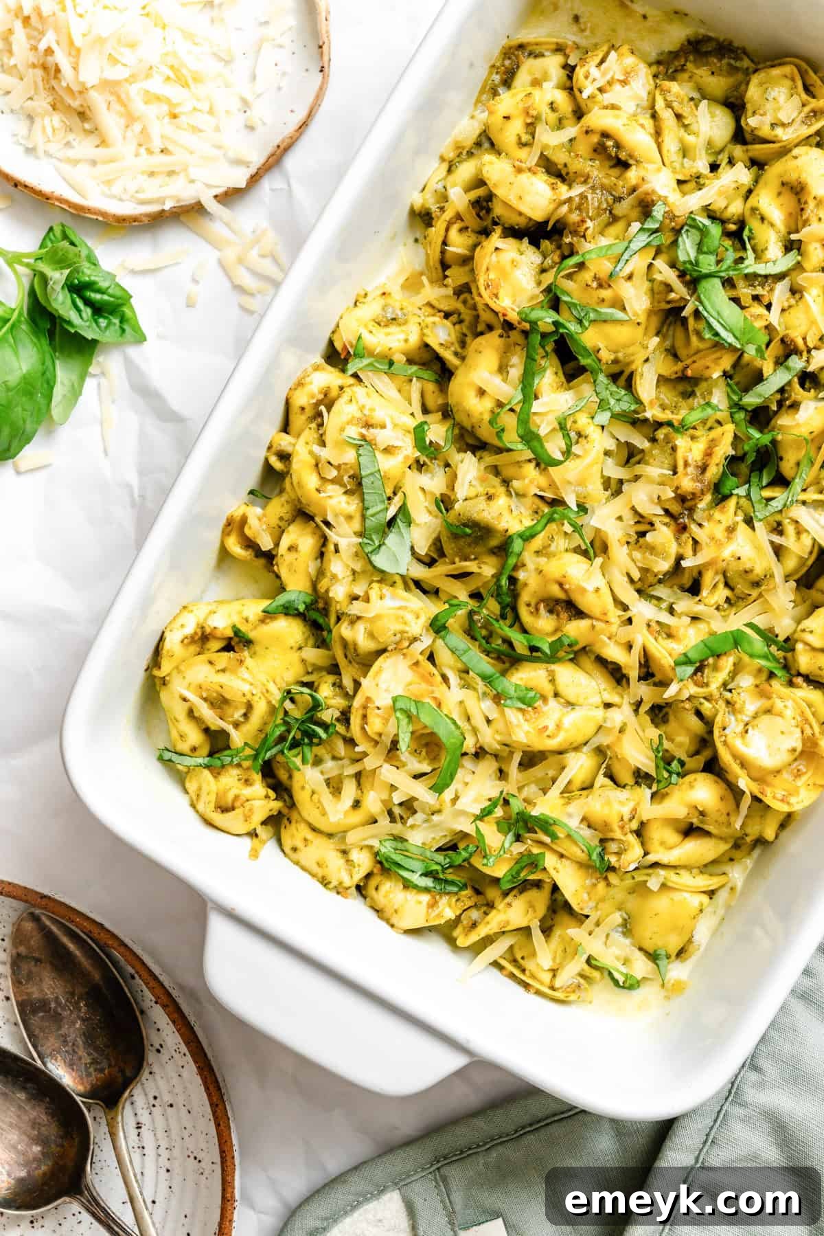 Baked pesto tortellini in a white ceramic baking dish, ready for serving.