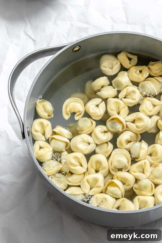 Fresh tortellini boiling gently in a pot of salted water on a stovetop.