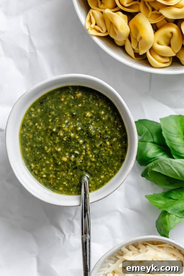 A small bowl of vibrant green pesto sauce, ready to be mixed with pasta.