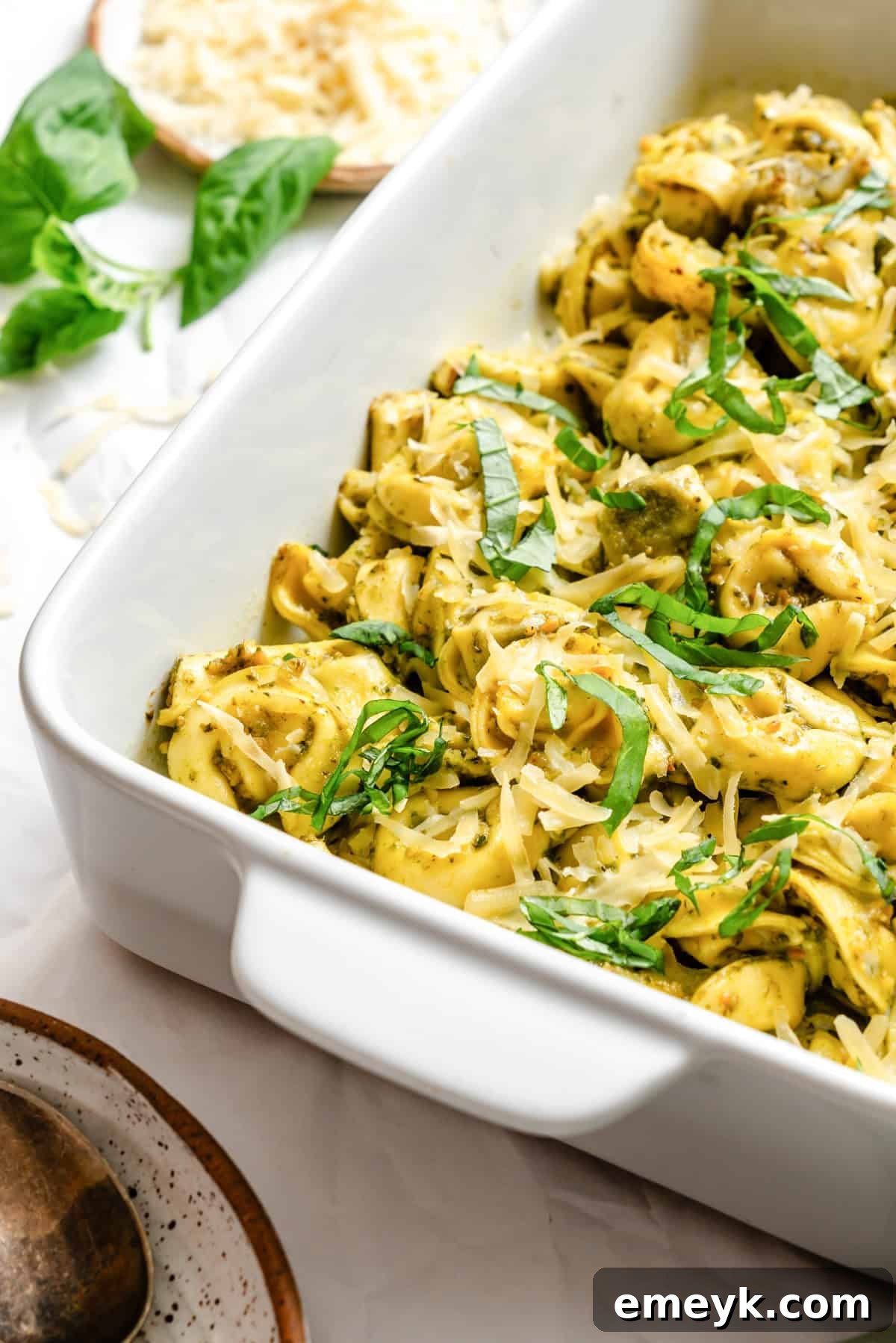 The finished Cheesy Pesto Tortellini dish, beautifully topped with fresh basil and more grated Parmesan cheese, ready to be served.
